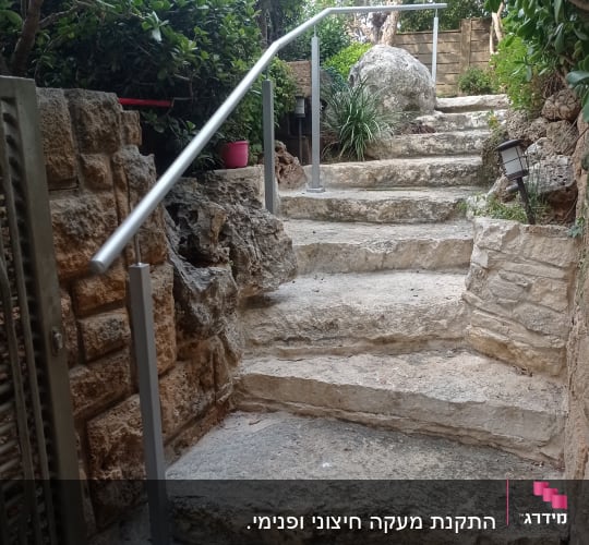 מעקה מתכת לאורך מדרגות אבן בגינה